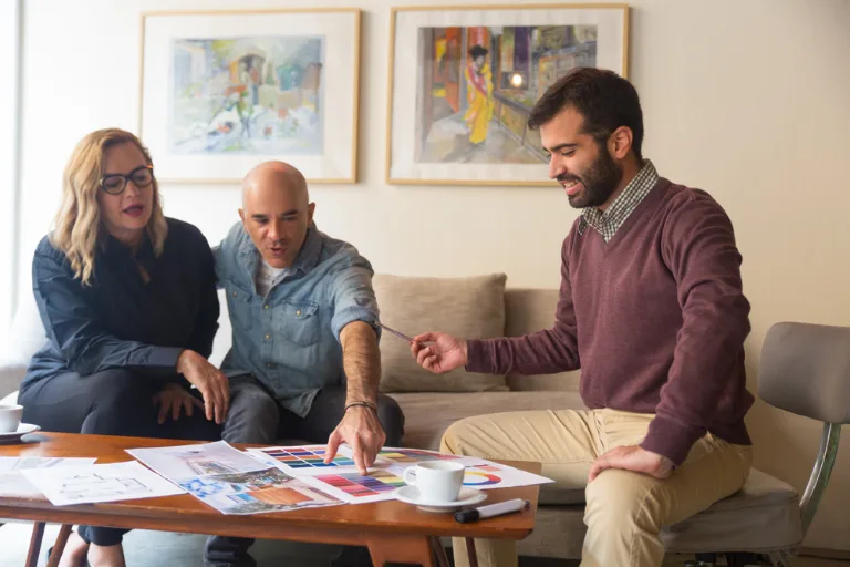 Interior designer explaining a detailed project budget with cost estimates, material samples, and construction plans during a client consultation